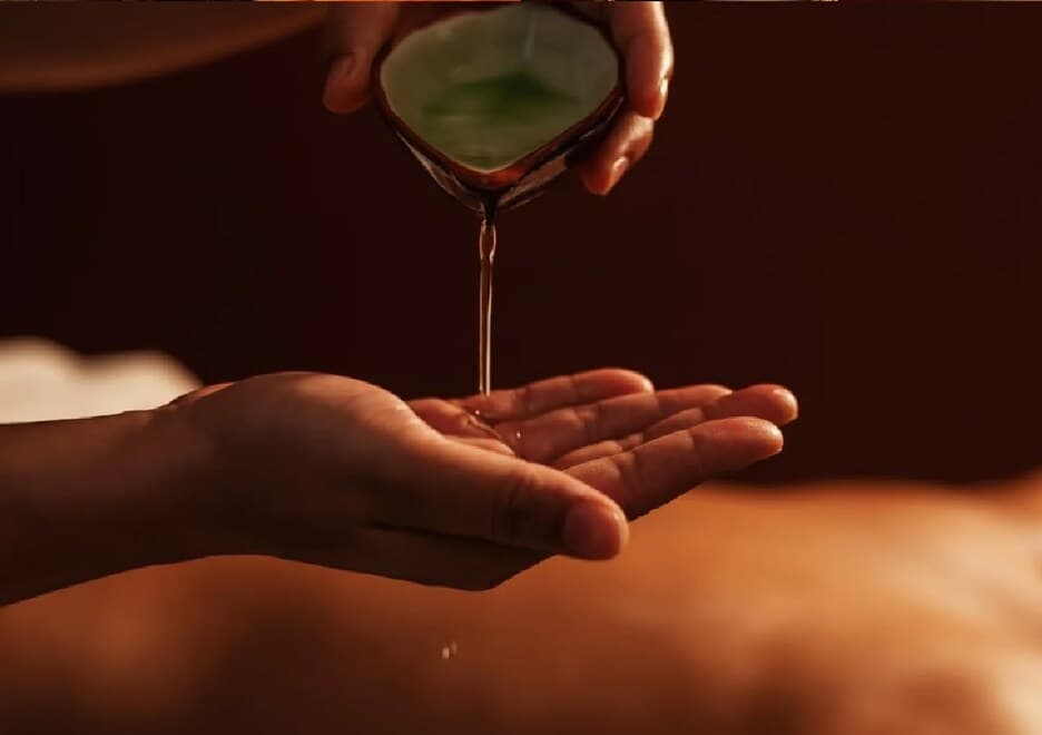 Warm herbal oil being prepared for a massage